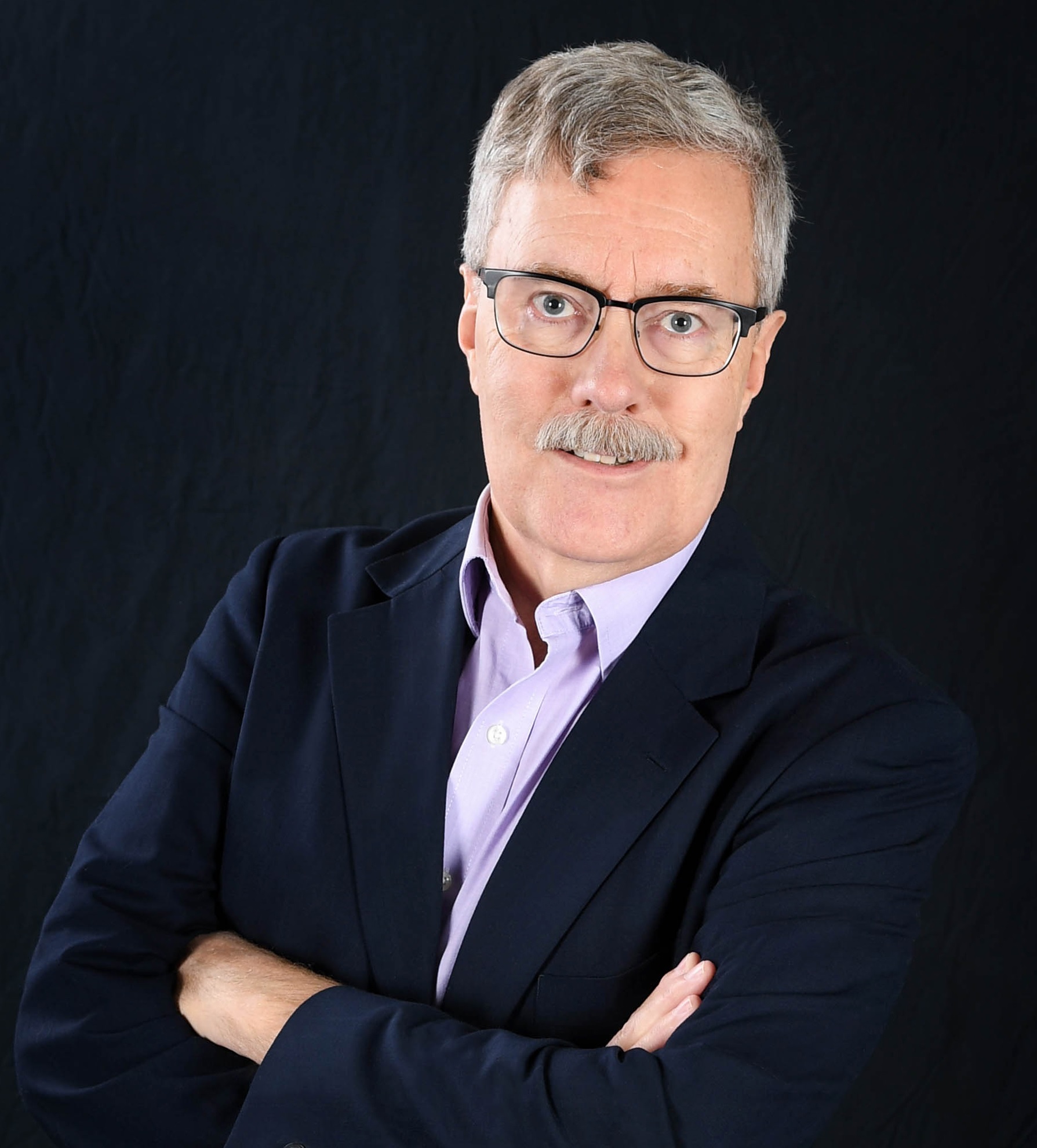 A man with glasses and a beard wearing a suit